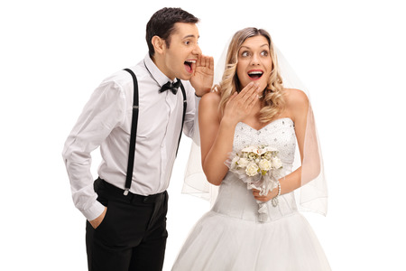 Young newlywed couple gossiping among each other isolated on white backgroundの写真素材