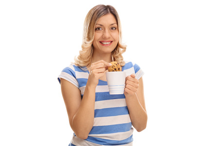 Smiling woman dipping a cookie in a glass of milk isolated on white backgroundの写真素材