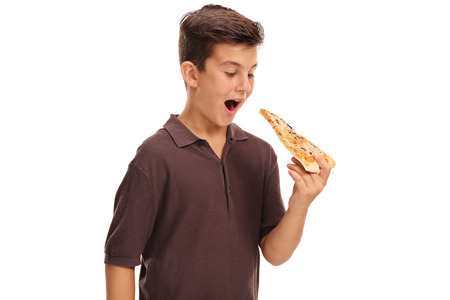 Little boy having a piece of pizza isolated on white backgroundの写真素材