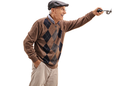 Excited elderly man honking a horn isolated on white backgroundの写真素材
