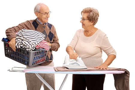 Senior couple ironing together and looking at each other isolated on white backgroundの写真素材