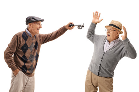 Senior honking a horn and scaring another senior isolated on white backgroundの写真素材