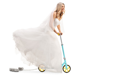 Full length portrait of a newlywed bride riding a scooter isolated on white backgroundの写真素材