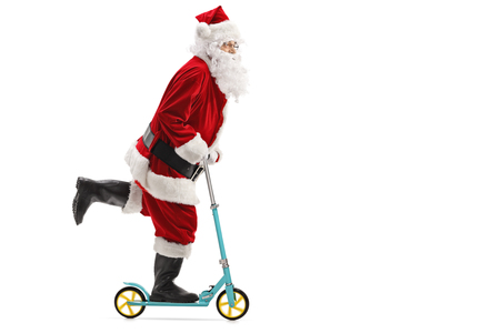 Full length profile shot of santa claus riding a scooter isolated on white backgroundの写真素材