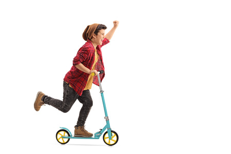 Full length portrait of an excited little boy riding a scooter and gesturing with his hand isolated on white backgroundの写真素材