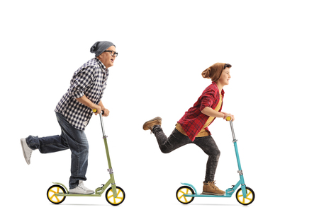 Full length portrait of a mature hipster and a boy riding scooters isolated on white backgroundの写真素材