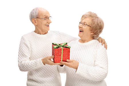 Cheerful elderly couple exchanging gifts isolated on white backgroundの写真素材