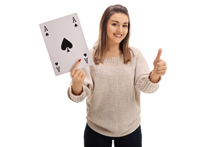 Joyful girl holding an ace of spades card and giving a thumb up isolated on white backgroundの写真素材