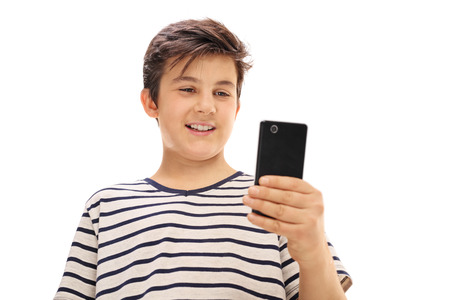Boy looking at a phone and smiling isolated on white backgroundの写真素材