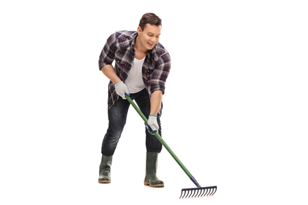 Young gardener using a rake isolated on white backgroundの写真素材
