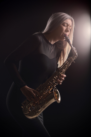 Female jazz musician playing a saxophone during a concertの写真素材