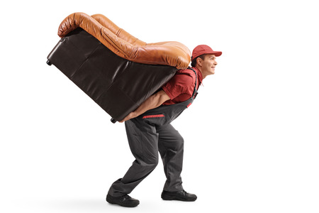 Profile shot of a mover carrying an armchair on his back isolated on white backgroundの写真素材