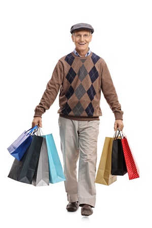 Full length portrait of an elderly man carrying shopping bags and walking towards the camera isolated on white backgroundの写真素材