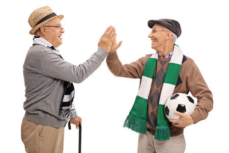 Two elderly soccer fans high-fiving each other isolated on white backgroundの写真素材