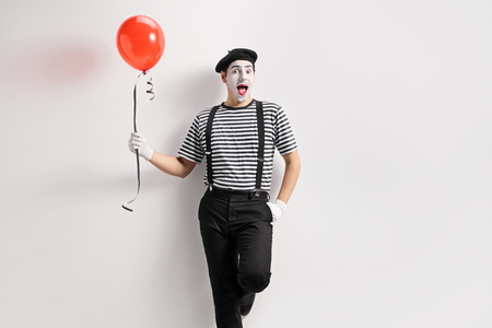 Mime holding a balloon and leaning against a wallの写真素材