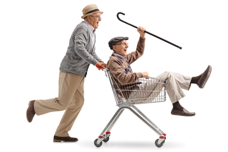 Senior pushing another senior in a shopping cart isolated on white backgroundの写真素材