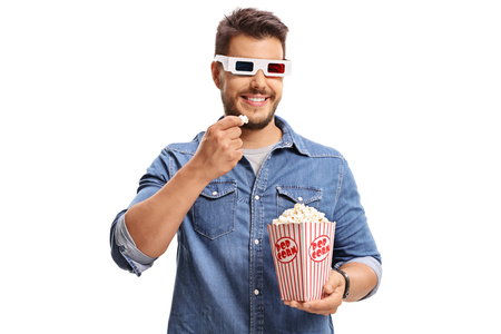 Man wearing a pair of 3D glasses and eating popcorn isolated on white backgroundの写真素材