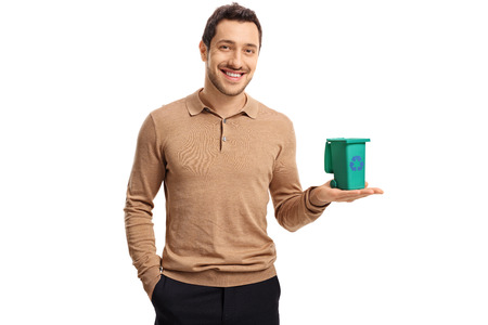 Young guy holding a small recycling bin and smiling isolated on white backgroundの写真素材