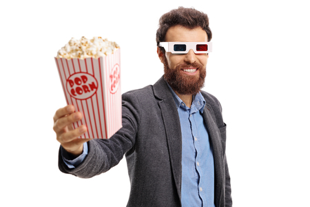 Bearded guy wearing 3D glasses and giving popcorn isolated on white backgroundの写真素材