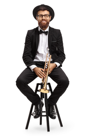 Trumpet player sitting on a chair and looking at the camera isolated on white backgroundの写真素材