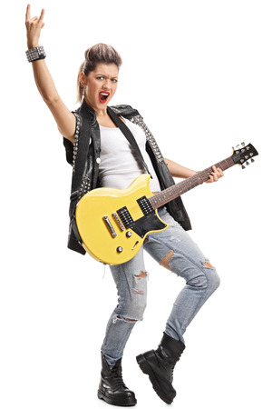 Full length portrait of a punk girl with an electric guitar making a rock hand gesture isolated on white backgroundの写真素材