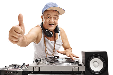 Elderly DJ playing music on a turntable and making a thumb up sign isolated on white backgroundの写真素材