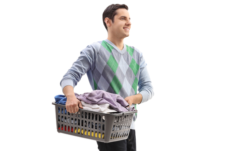 Young man holding a laundry basket full of clothes isolated on white backgroundの写真素材