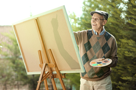 Elderly man painting on a canvas outdoorsの写真素材