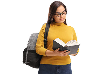 Female teen student with a backpack reading a book isolated on white backgroundの写真素材