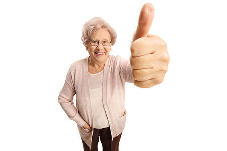 Elderly woman making a thumb up sign and smiling isolated on white backgroundの写真素材