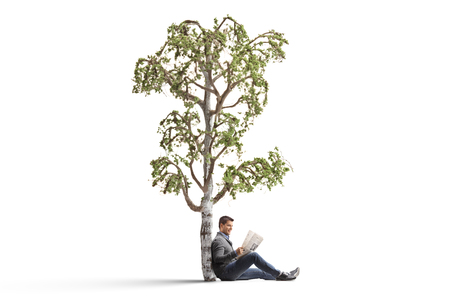 Young man reading a newspaper under a birch tree isolated on white backgroundの写真素材