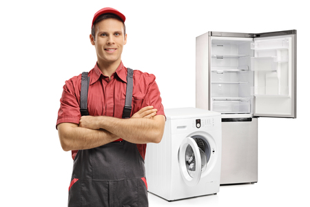 Repairman with his arms folded in front of a washing machine and a refrigerator isolated on white backgroundの写真素材