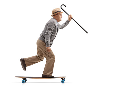 Full length profile shot of a mature man with a cane riding a longboard isolated on white backgroundの写真素材