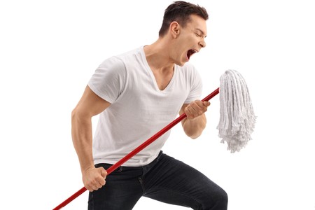Young man singing on a mop isolated on white backgroundの写真素材
