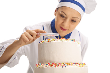 Female chef putting sprinkles on a cake isolated on white backgroundの写真素材