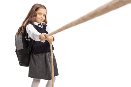 Little schoolgirl pulling a rope isolated on white backgroundの写真素材