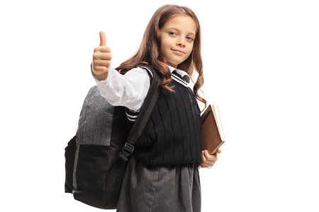 Schoolgirl with a backpack and a book making a thumb up gesture isolated on white backgroundの写真素材