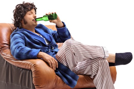 Man sitting in a leather armchair and having a beer isolated on white backgroundの写真素材