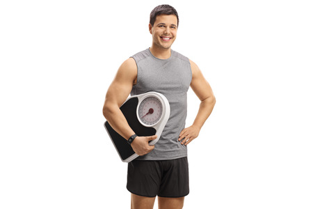 Young man in sportswear holding a weight scale isolated on white backgroundの写真素材