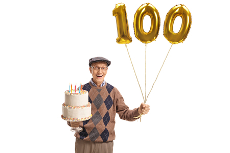 Happy senior with a birthday cake and a number hundred balloon isolated on white backgroundの写真素材