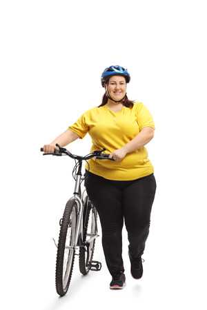 Full length portrait of an overweight woman with a bicycle walking towards the camera isolated on white backgroundの写真素材