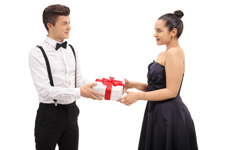 Formally dressed teenage boy giving a gift to his girlfriend isolated on white backgroundの写真素材