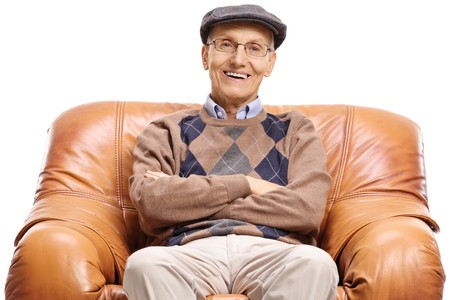 Senior seated in a leather armchair smiling isolated on white background