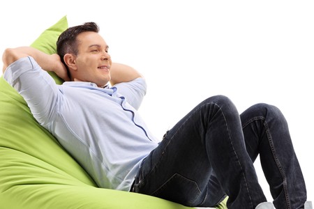 Relaxed young man sitting on a beanbag isolated on white backgroundの写真素材