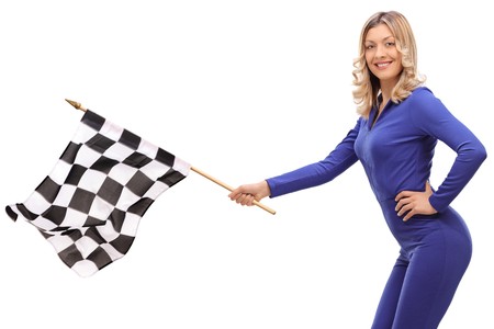 Young woman in a racing suit waving a checkered race flag isolated on white backgroundの写真素材