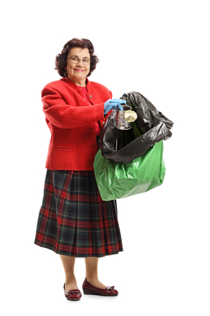 Full length portrait of an elderly woman throwing a tin can in a garbage bag isolated on white backgroundの写真素材