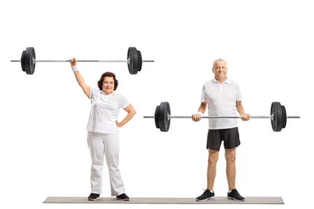 Full length portrait of an elderly woman and an elderly man lifting barbells isolated on white backgroundの写真素材