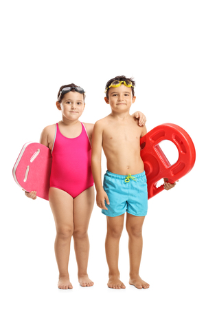 Full length portrait of a little girl and a boy in swimming suits holding swimming pads isolated on white backgroundの写真素材