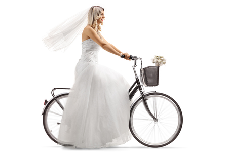 Young bride riding a bicycle isolated on white backgroundの写真素材