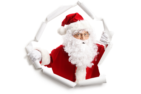 Santa Claus emerging from a paper hole isolated on white backgroundの写真素材